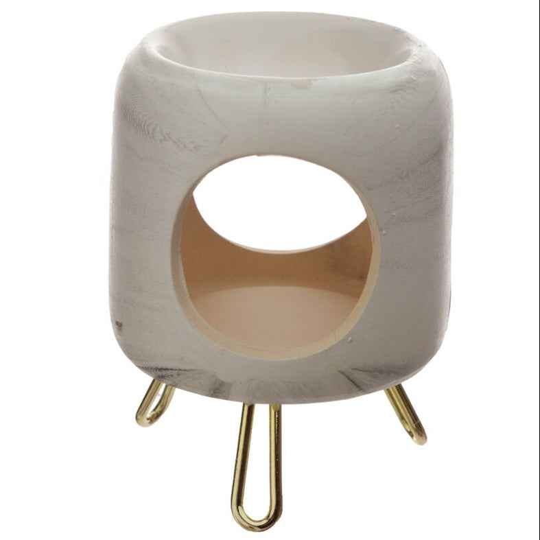 El Quemador de Cera Fundida Cerámica Fleur-de-Bois - Casa Dorada en blanco mate marmoleado en gris es un portavelas moderno con diseño cilíndrico y base de tres patas doradas, ideal para aromatizar tu hogar con estilo.