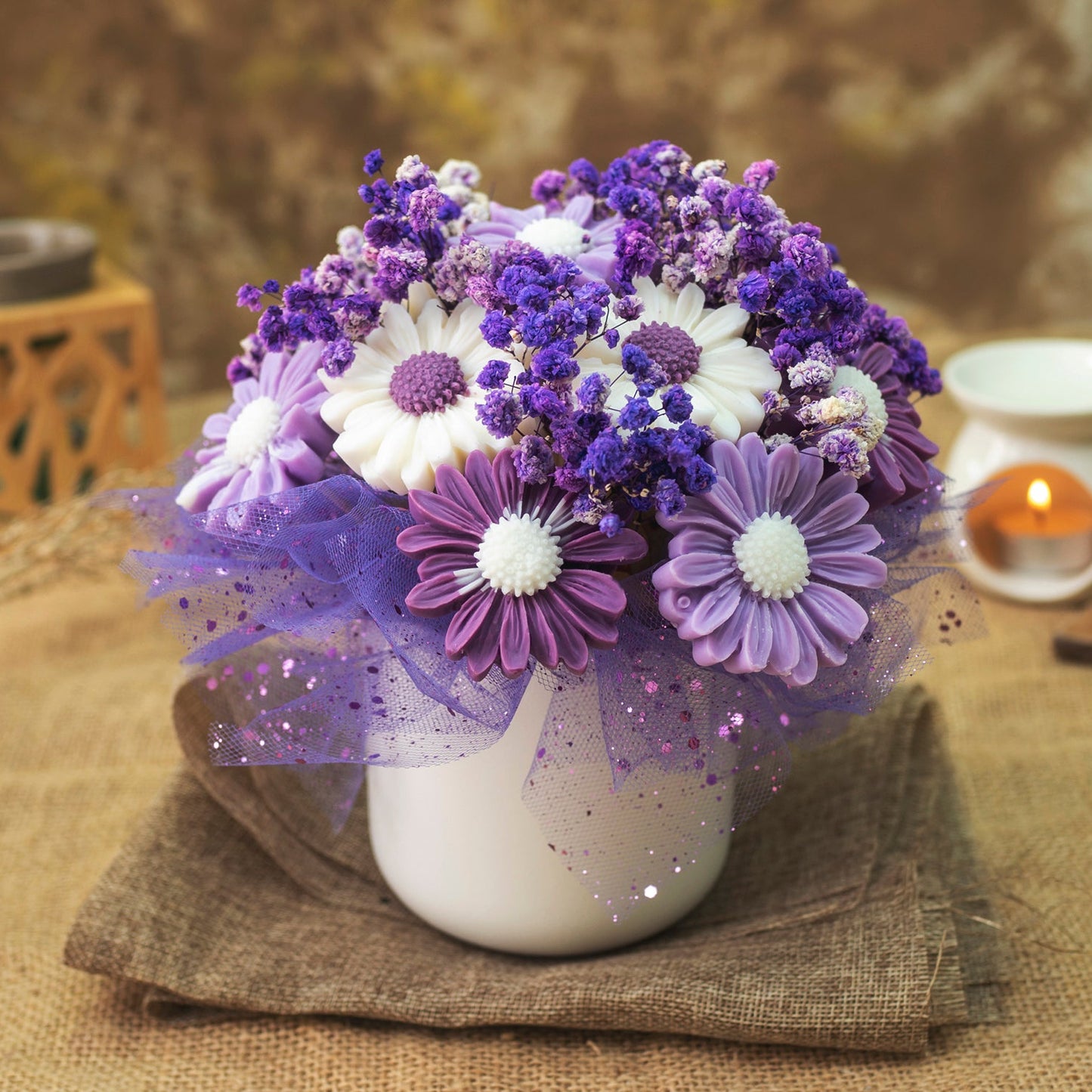 El Ramo de Flores Fleur-de-Bois Margaritas Clásico de Cera de Soja FRESCURA DE LAVANDA presenta flores blancas, lavanda y moradas parecidas a margaritas con velas derretidas florales en brillante tul morado-un regalo romántico de ensueño.