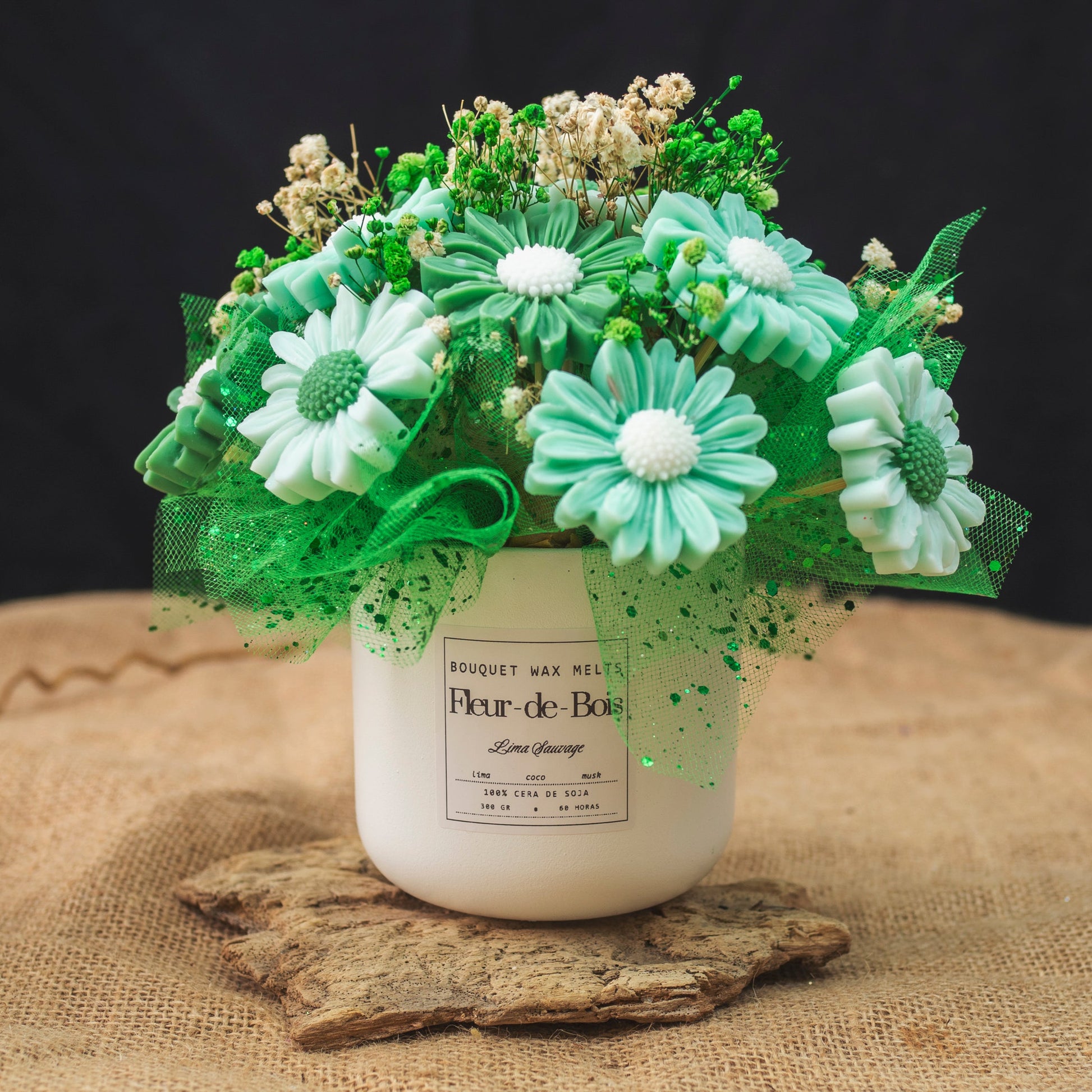 El Ramo de Flores Margaritas Clásico de Cera de Soja LIMA SAUVAGE se presenta en un tarro blanco con tul verde y capullos de nata, un regalo romántico ideal, expuesto sobre arpillera y madera sobre un fondo negro.