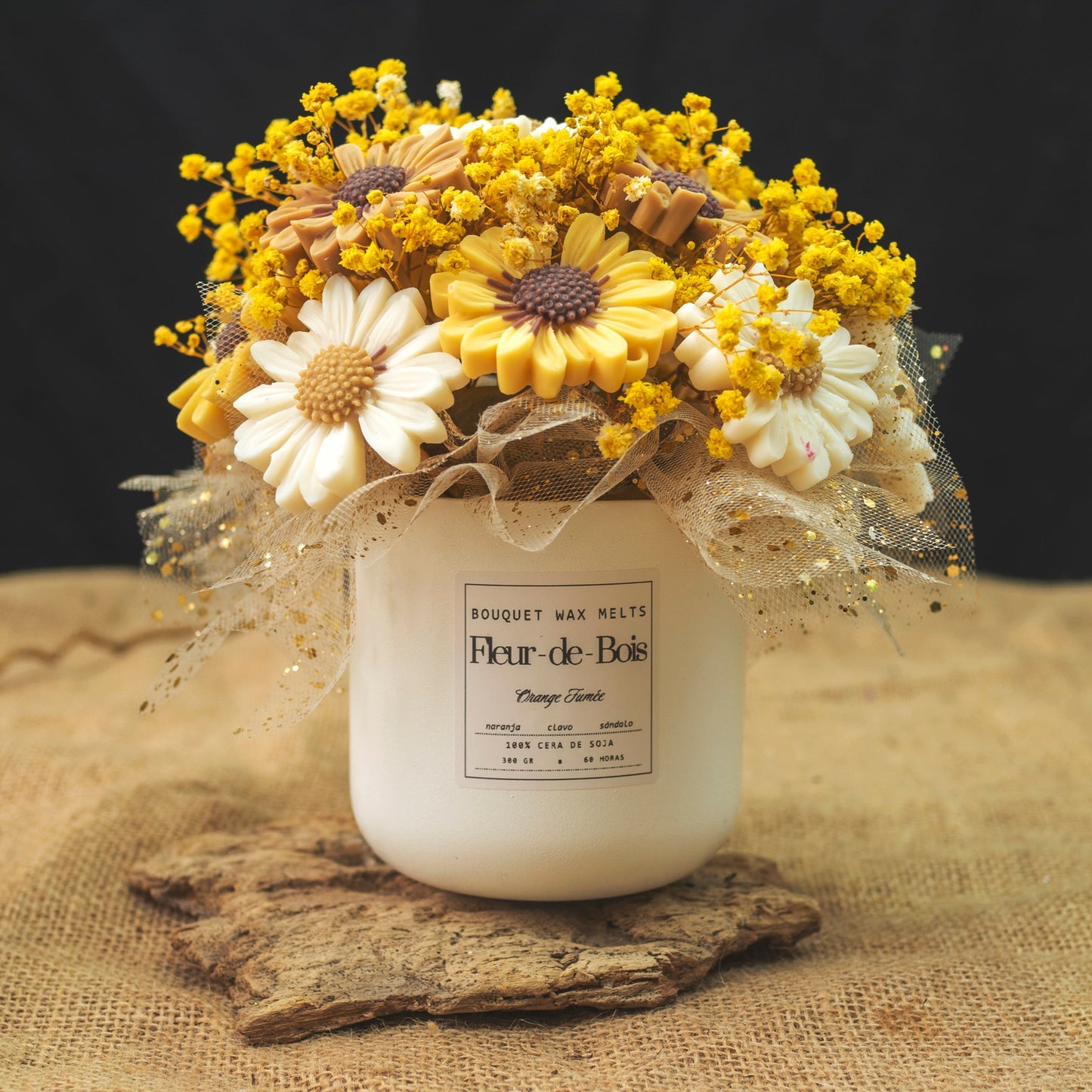 Un tarro blanco con la etiqueta "Fleur-de-Bois" contiene el Ramo de Flores Margaritas Clásico de Cera de Soja Fleur-de-Bois ORANGE FUMÉE, adornado con cinta de malla dorada y flores secas amarillas: un encantador regalo romántico.