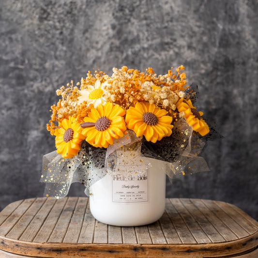 Un jarrón blanco con etiqueta exhibe las Margaritas Ramo de Flores Clásico de Cera de Soja PEAKY SPOOKY de Fleur-de-Bois - flores en cera de soja y secas blancas y naranjas con una cinta de puntos - sobre una mesa de madera rústica, perfectas como regalo romántico.