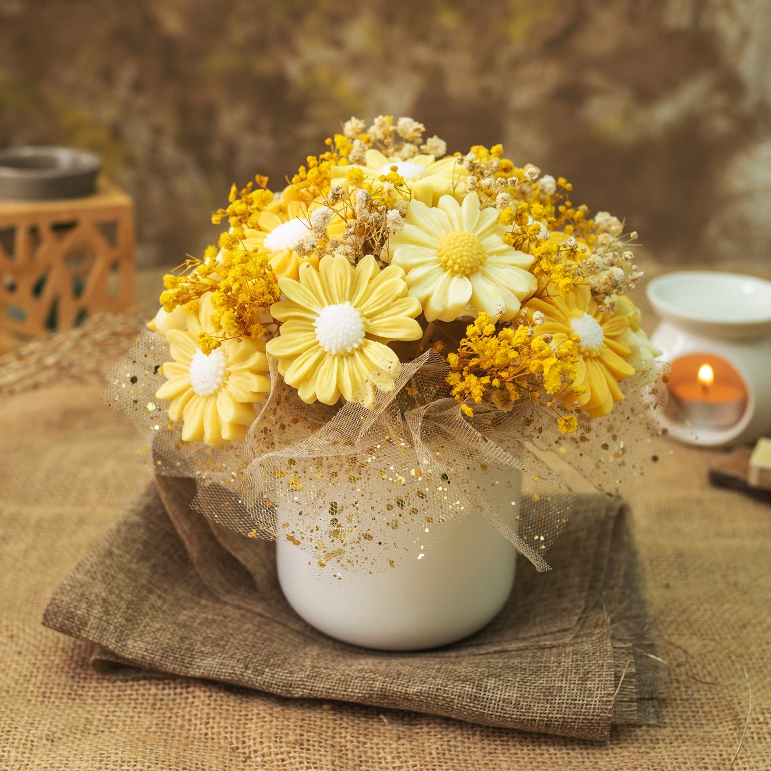 El Ramo de Flores Margaritas de Cera de Soja PIE DE LIMÓN de Fleur-de-Bois combina margaritas blancas y amarillas con pequeños toques dorados, envuelto en malla decorativa dorada, ideal como regalo romántico y elegante.