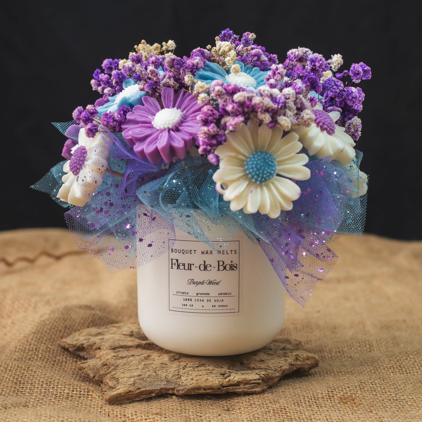 El Ramo de Flores Fleur-de-Bois Margaritas Clásico de Cera de Soja MADERA MORADA presenta flores moradas, blancas y azules en un tarro blanco, acentuado con malla azul brillante sobre arpillera y madera, lo que lo convierte en un regalo romántico perfecto.