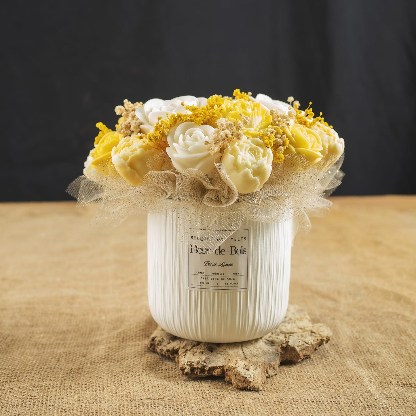 El ramo «Ramo de Peonias y Rosas Clásico de Cera de Soja PIE DE LIMÓN» de Fleur-de-Bois cuenta con flores artificiales blancas y amarillas, complementadas con flores de relleno amarillas y una cinta de malla beige, todo ello en un jarrón blanco con textura, ideal como regalo único para cualquier ocasión.