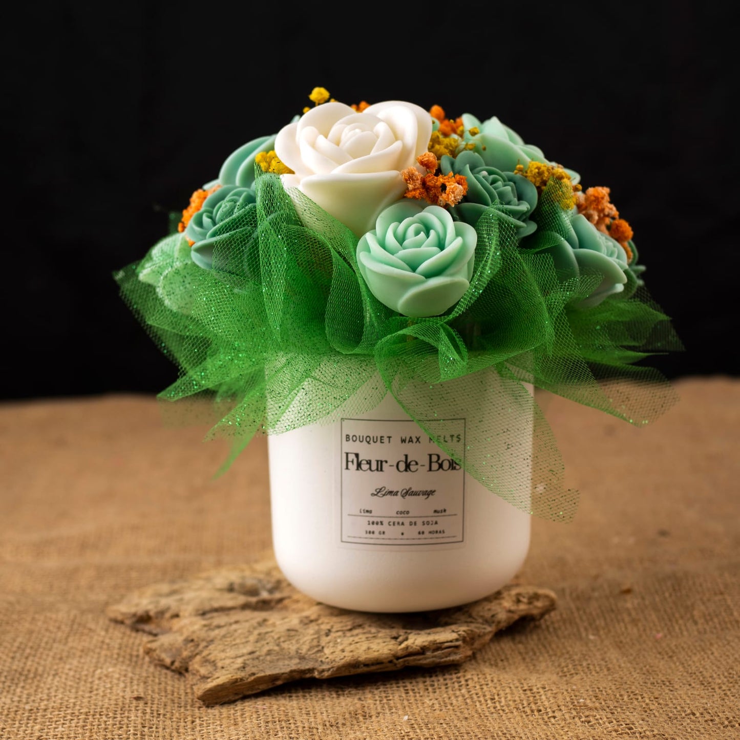 El "Ramo de Rosas Clásico de Cera de Soja LIMA SAUVAGE" Fleur-de-Bois se presenta en un tarro blanco con flores artificiales verdes y blancas, reflejos amarillos y red: un elegante y romántico regalo sobre un fondo de madera oscura.