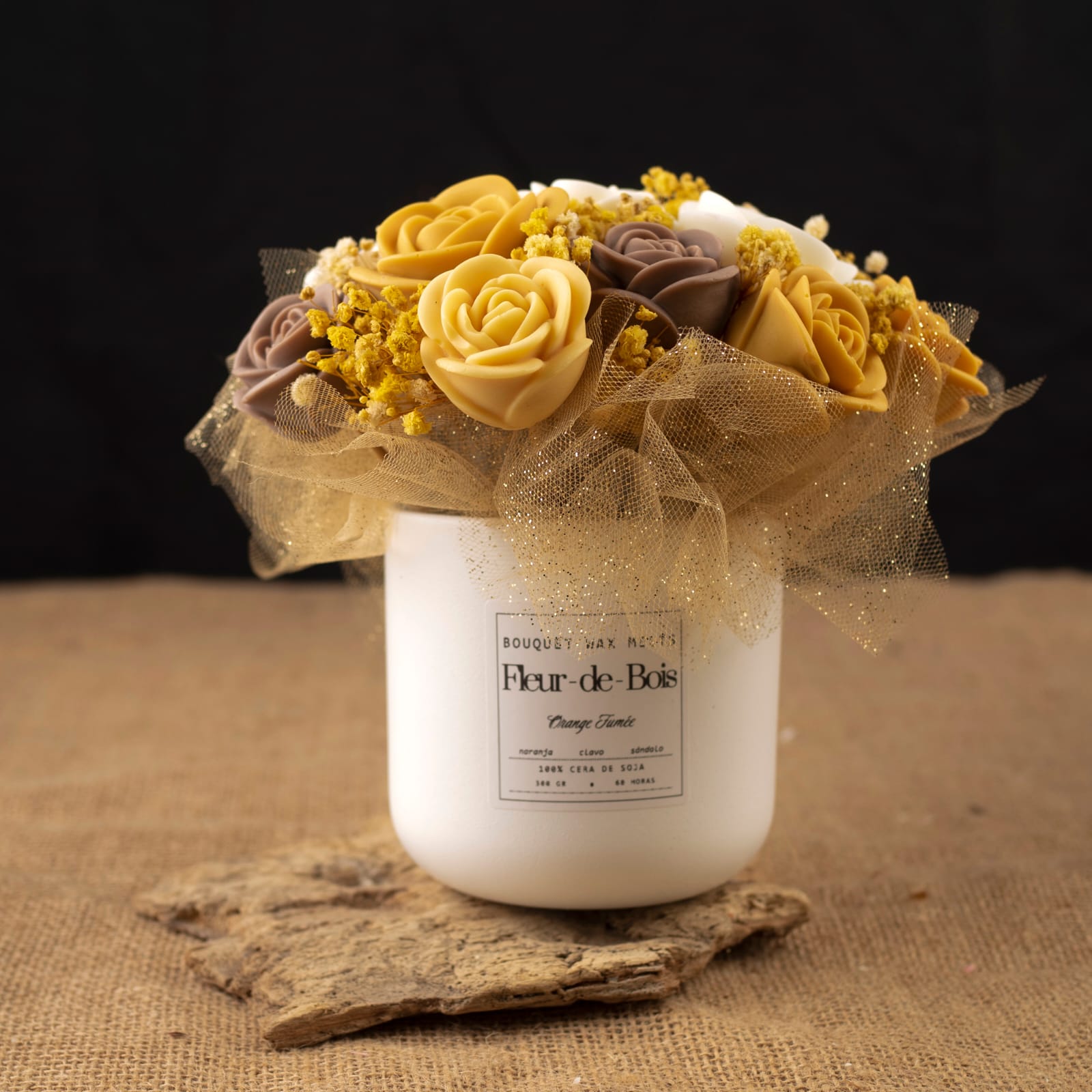 Un tarro Fleur-de-Bois blanco con la etiqueta "Ramo de Rosas Clásico de Cera de Soja ORANGE FUMÉE" muestra rosas amarillas, crema y marrones con detalles de malla dorada: un regalo romántico y encantador sobre una superficie de madera rústica con fondo negro.
