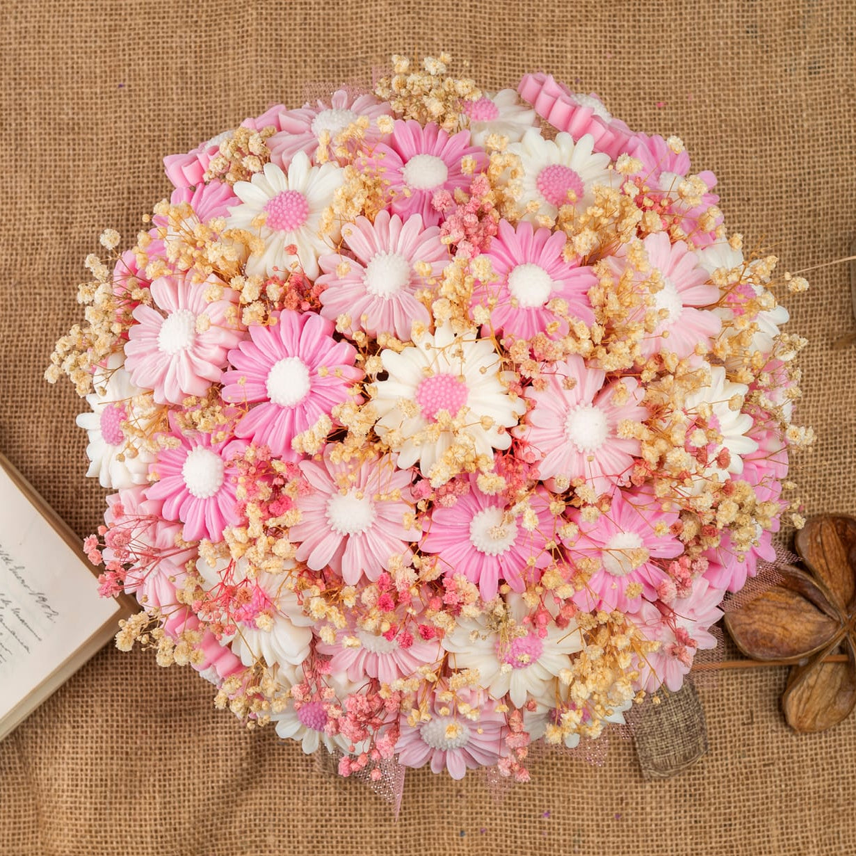 El Ramo de Margaritas GRANDE de Cera de Soja de Fleur-de-Bois, con flores rosas y blancas y flores secas beige, dispuestas sobre arpillera con un libro y hojas, es ideal como regalo romántico o emparejado con velas derretidas florales.