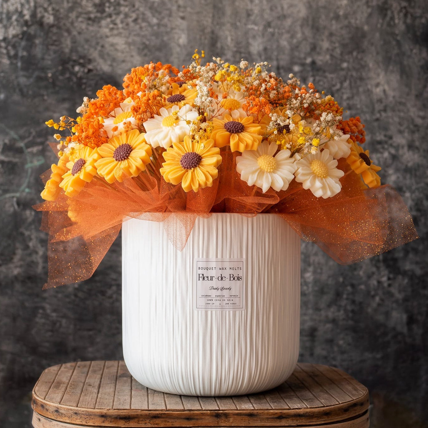 El Ramo de Margaritas XL de Cera de Soja de Fleur-de-Bois presenta una vibrante mezcla de flores naranjas, amarillas y blancas, aliento de bebé y tul naranja: un regalo romántico ideal, expuesto sobre un fondo rústico de madera.