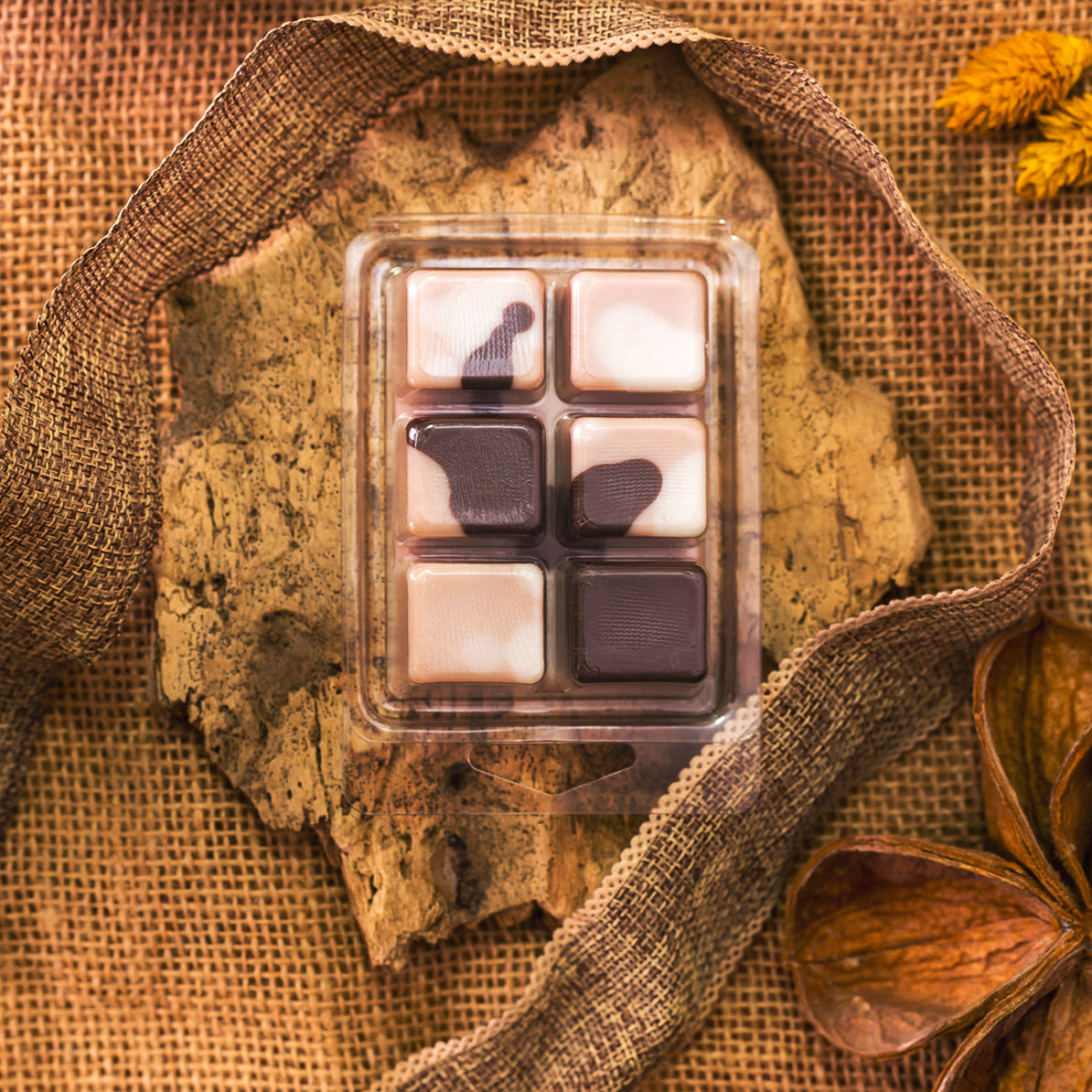 Un paquete de Wax Melts de cera de soja cuadrados y jaspeados hechos a mano en marrón y blanco. Fleur-de-Bois Wax Melts Barra de chocolate DOLCE CAFFÉ-personaliza tu aroma para un toque acogedor, acentuado con corteza rústica, arpillera, cinta y hojas secas.