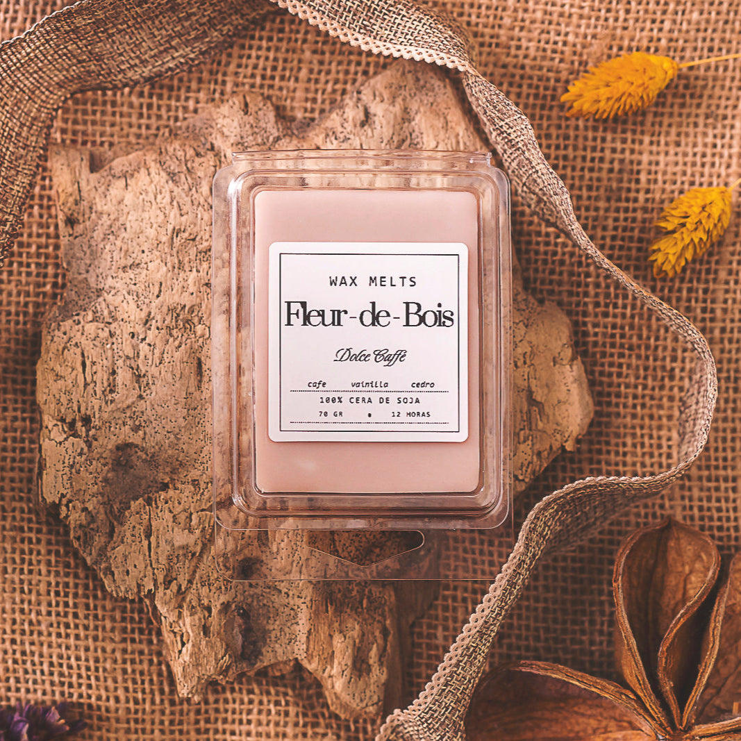 Un paquete de Wax Melts Fleur-de-Bois Barra de chocolate DOLCE CAFFÉ descansa sobre corteza de árbol con arpillera, flores secas y una cinta, creando un ambiente rústico y acogedor con aroma personalizado.