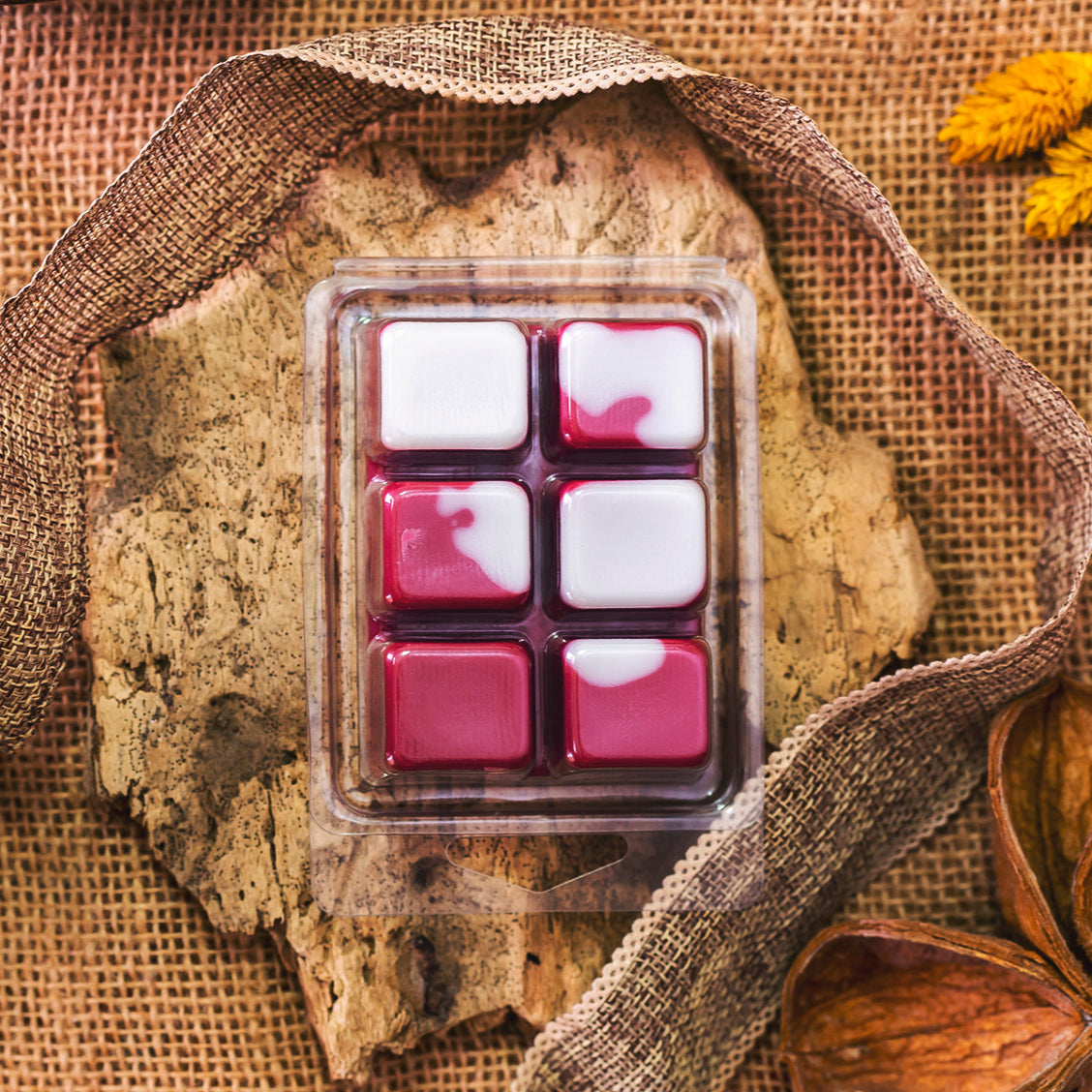 Un paquete de wax melts, hechos a mano Fleur-de-Bois Wax Melts Barra de chocolate ESPECIAS DE MADERA, rosa jaspeado y blanco, en la corteza con arpillera, hojas secas, y una flor amarilla. Hecho con cera de soja y fragancia de especias de madera.