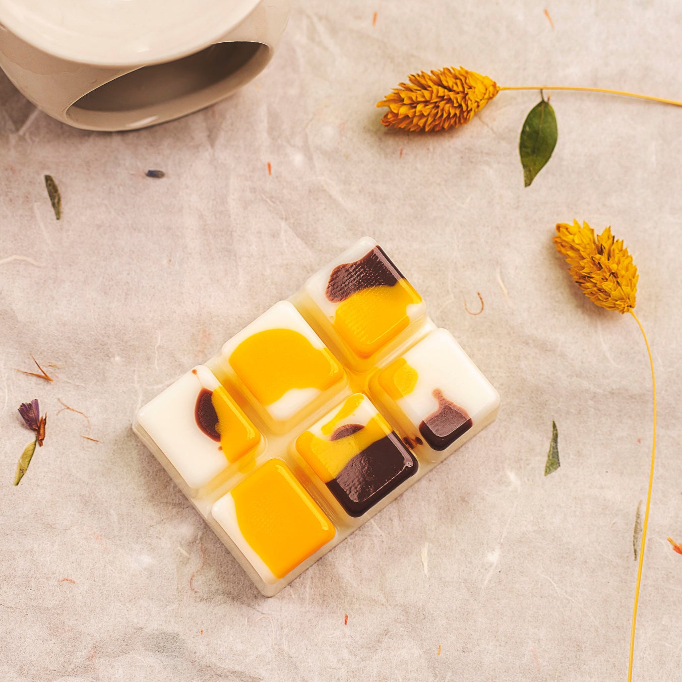 El wax melts Barra de chocolate Fleur-de-Bois ORANGE FUMÉE de Fleur-de-Bois presenta remolinos blancos, naranja y marron, bellamente presentados entre flores amarillas secas, un fundido de cera de soja que constituye un perfecto regalo personalizado.