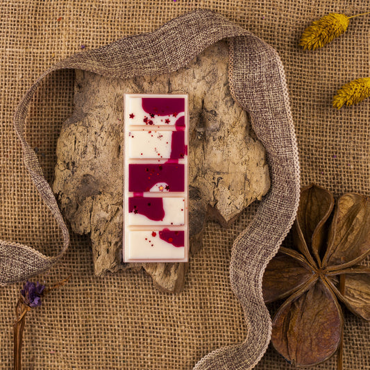 Las Melts de Cera Láminas Aromáticas Flor de Bois MADERA DE MEDIANOCHE se asemejan a una barra arremolinada que descansa sobre corteza, rodeada de arpillera, cinta, flores secas, anís estrellado, y exudan fragancias de primera calidad que recuerdan a la cera aromática.